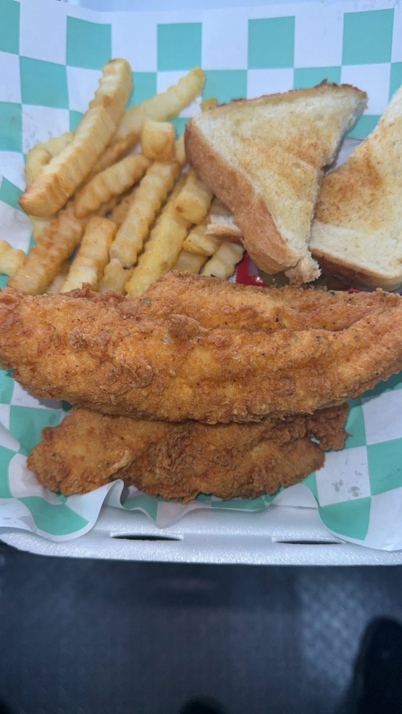Fried chicken tenders, crinkle-cut fries, and Texas toast in a checkered paper-lined basket.